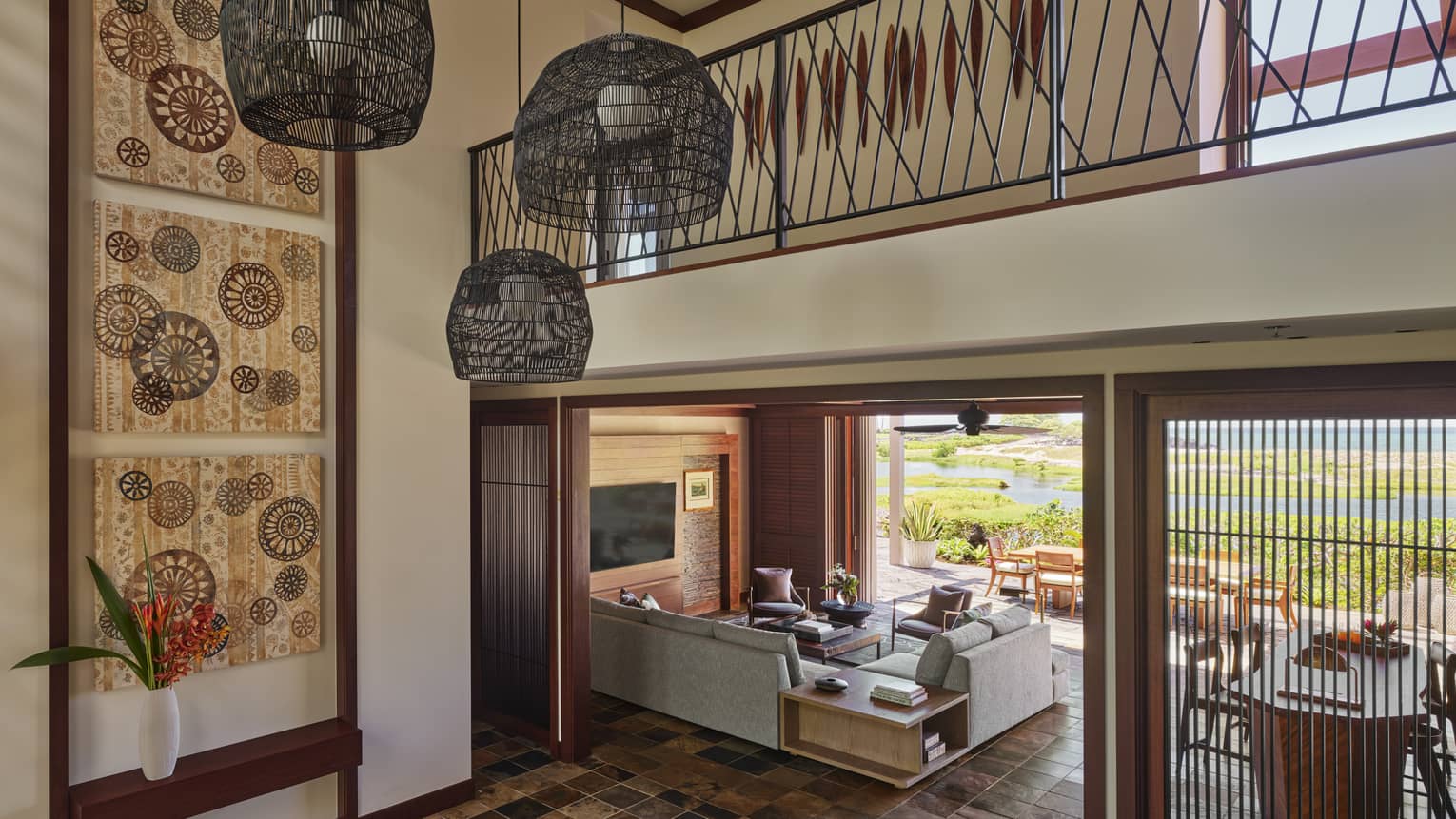 Two-storey foyer with three hanging lights, looking into living room area