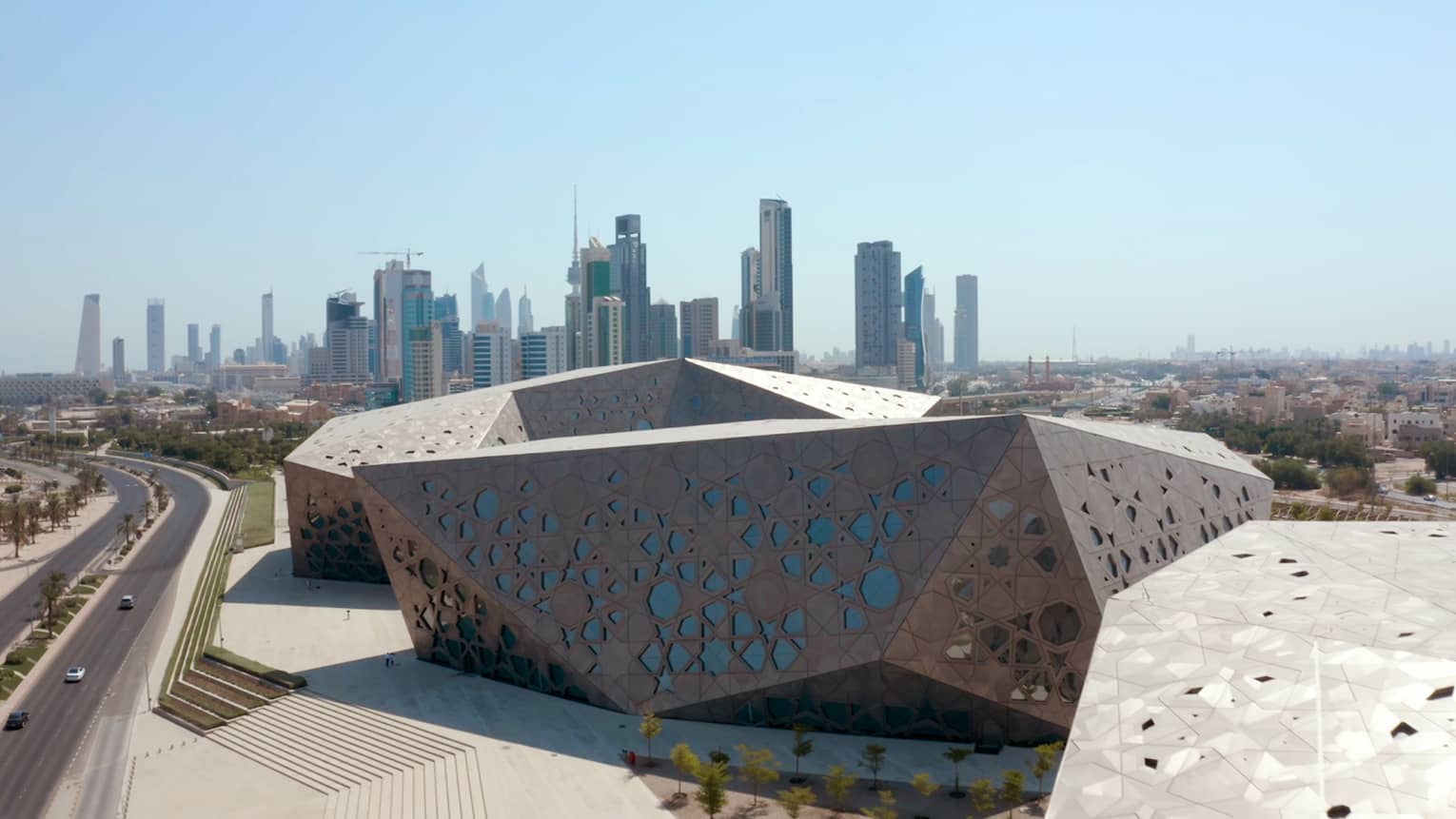 Metal-and-glass angluglar building with the Kuwait skyline in the background
