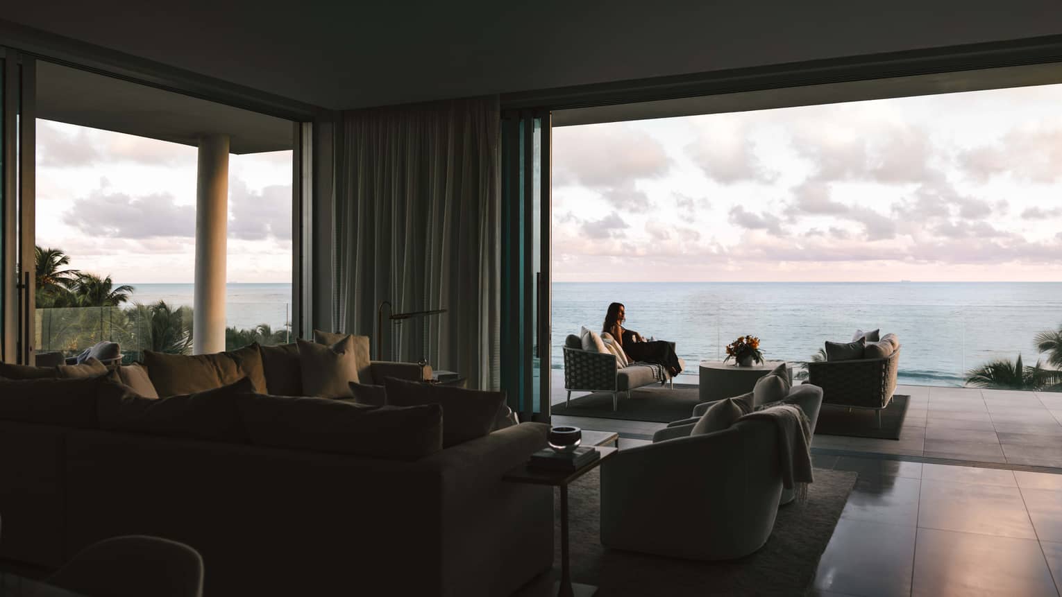 A woman sits on terrace of a contemporary ocean-view residence