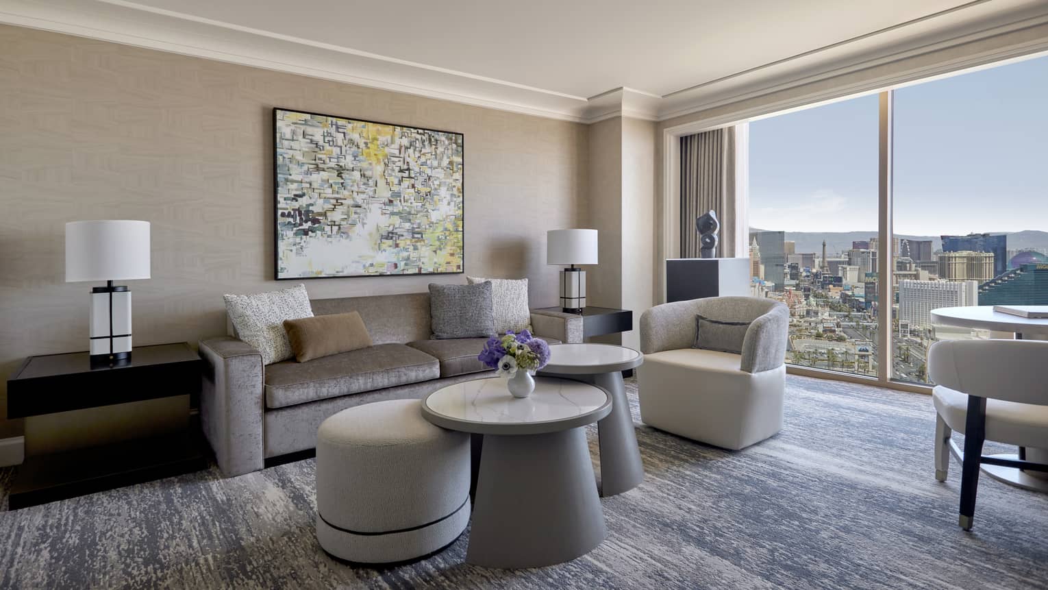 A sitting area with large window, sofa, coffee table, chairs, and small table.