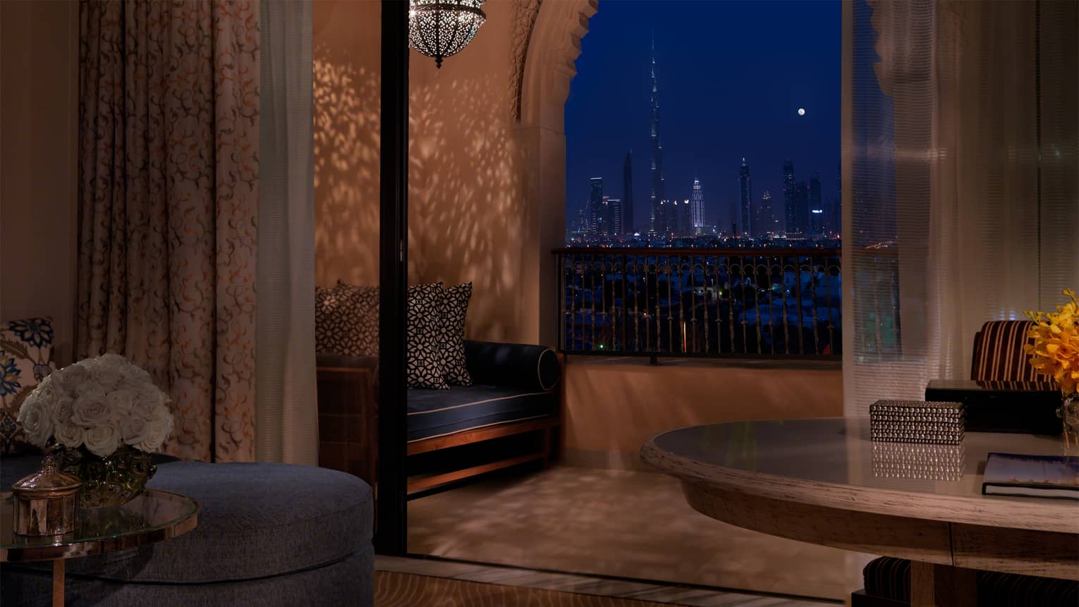 Night view of Premier Skyline room opening to patio with Moroccan-style chandelier and Dubai skyline