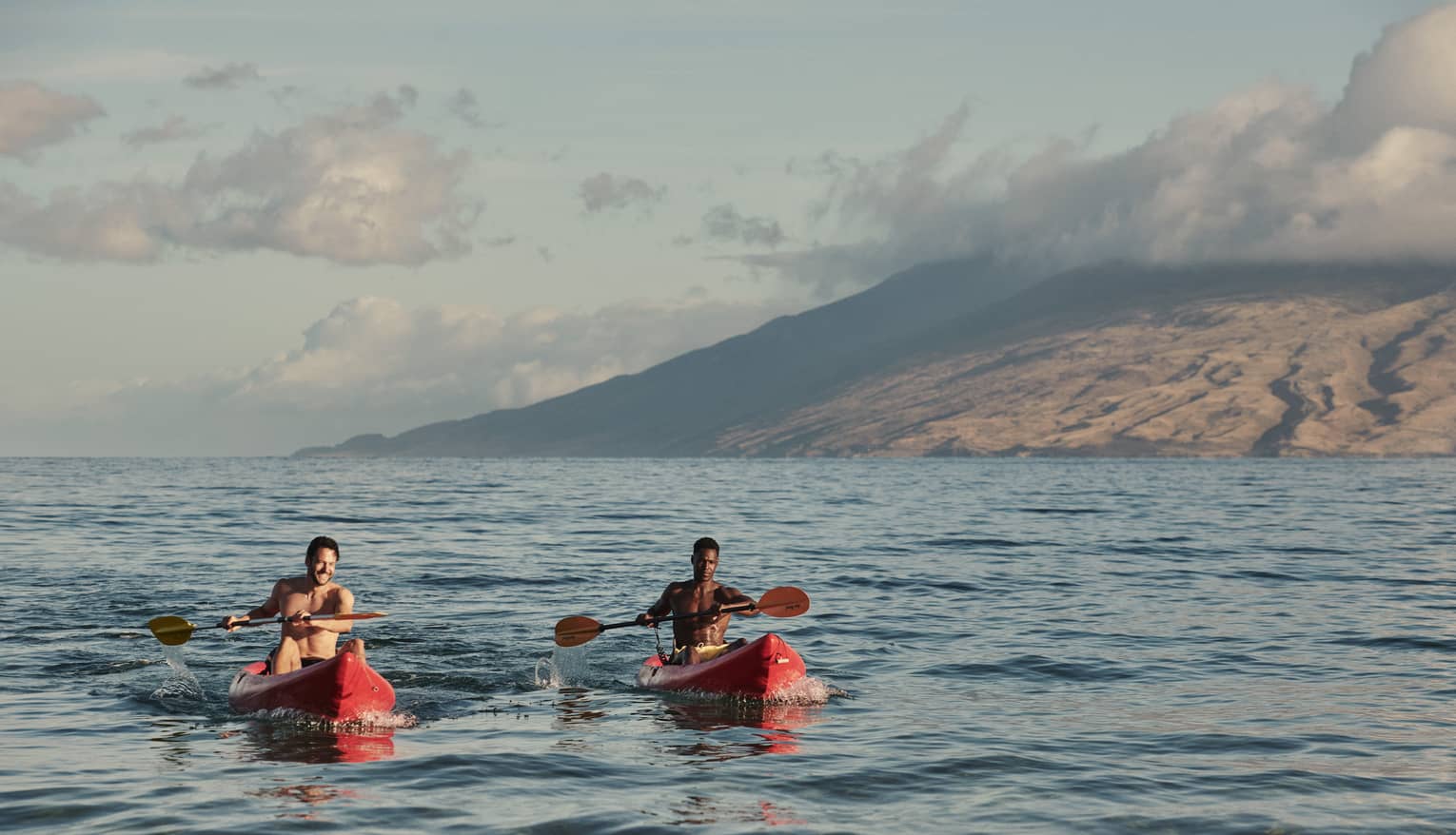 Two men in red kayaks in the ocean in Maui