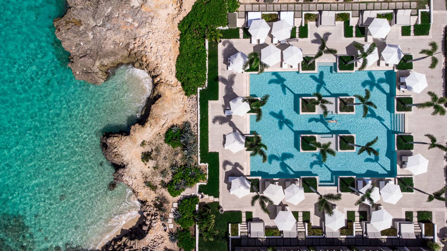 A pool next to the rocky shore of a beach.