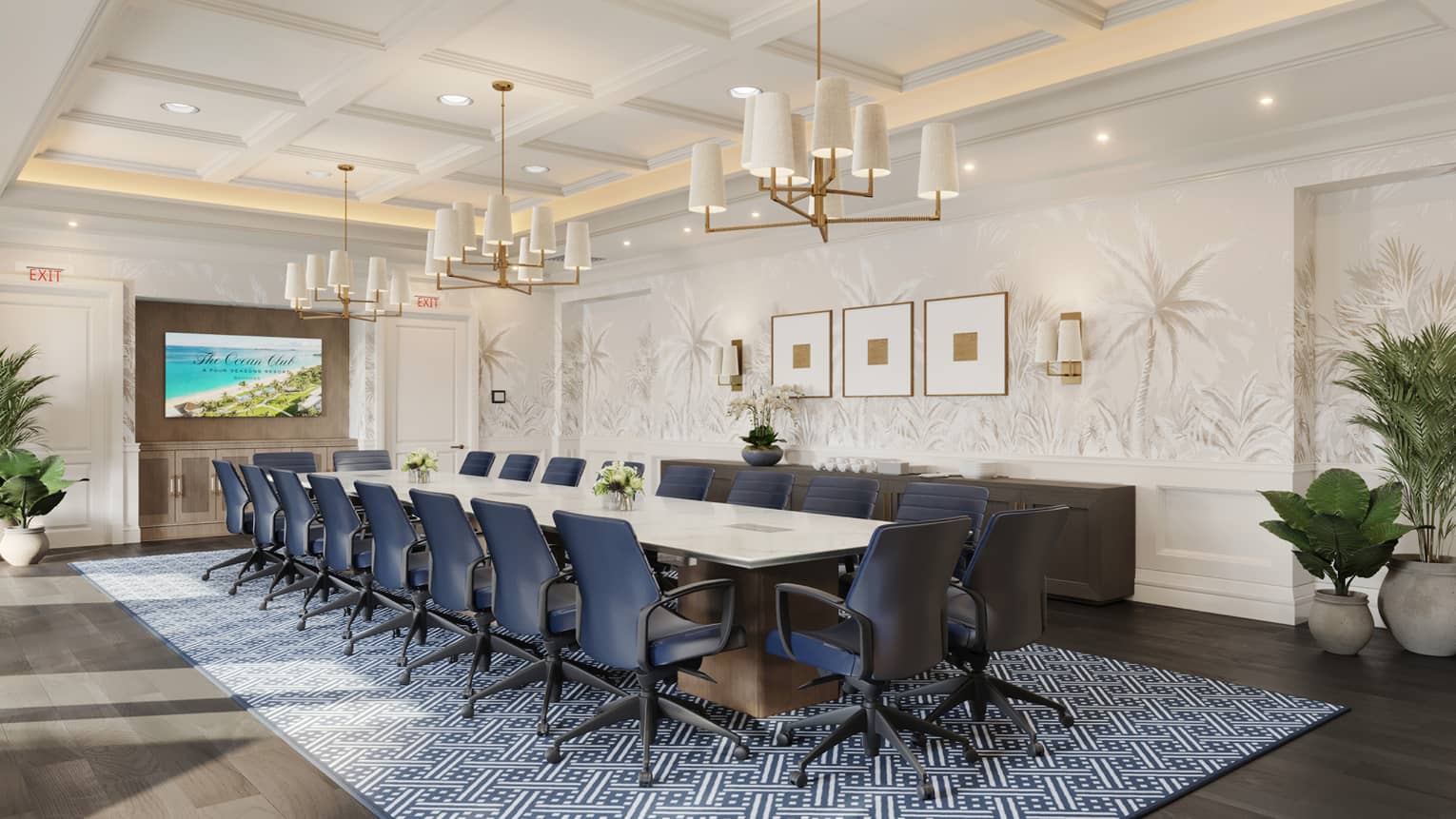 An elegant meeting room with subtle decor in various shades of white. A long table with comfortable chairs sits on a patterned area rug on a wood floor. There is a large flat-screen TV on one wall, natural light coming in large windows on another wall, and both ceiling and wall sconce lighting. The decor is accented by framed wall art and potted plants.