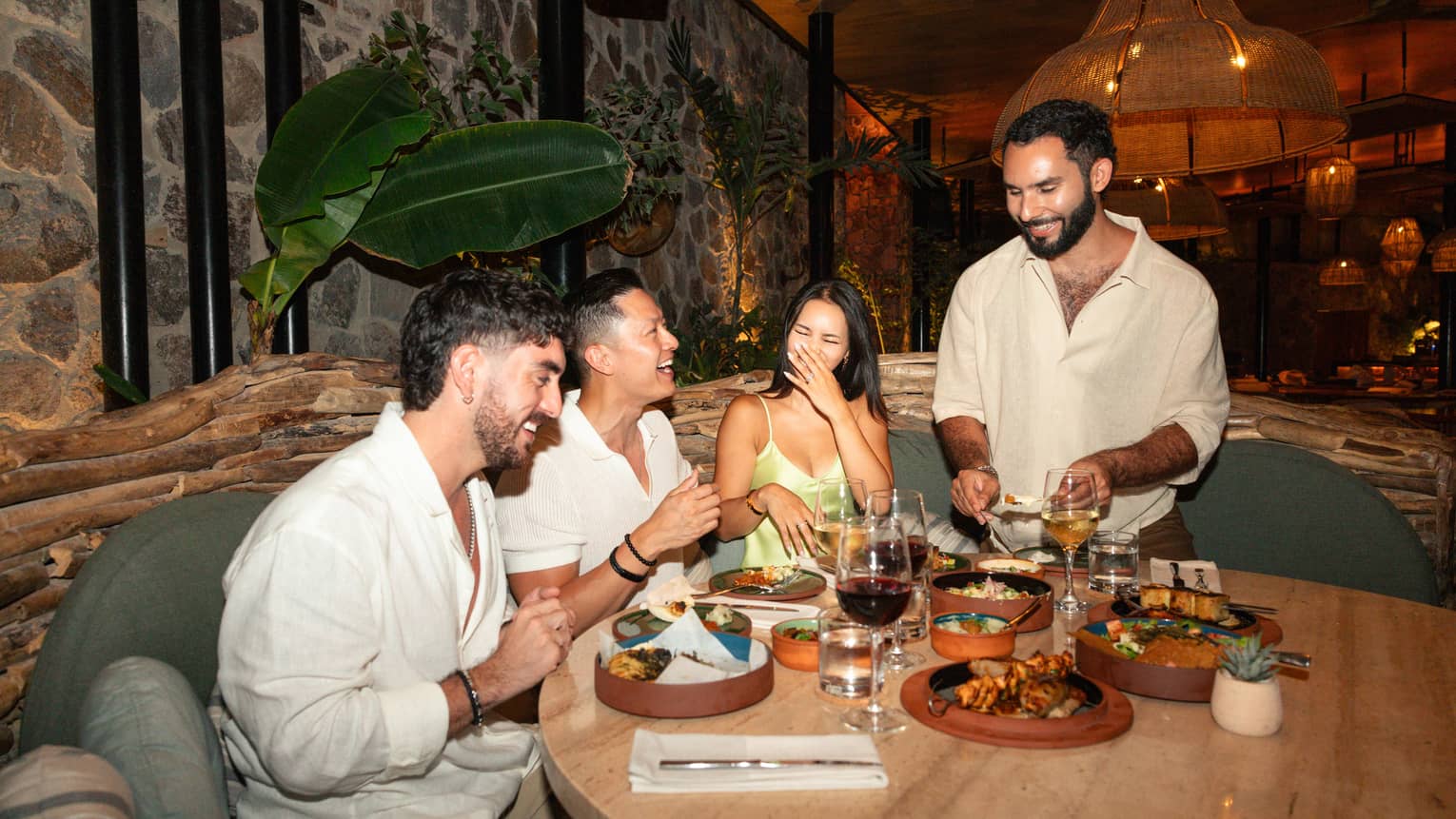 Four people sit around a restaurant table laughing and smiling