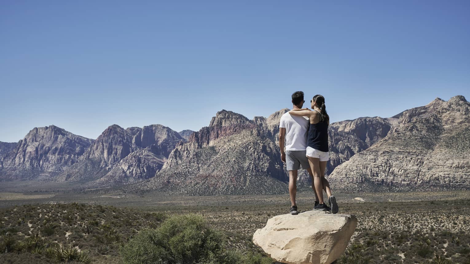 A man and woman outside looking at a mountain range.