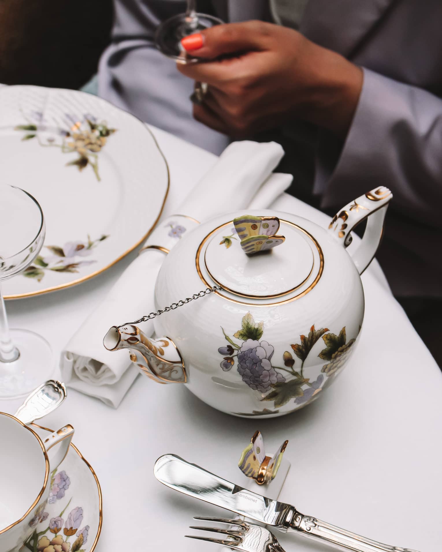 A white tea set with purple and yellow flowers on a white cloth table.