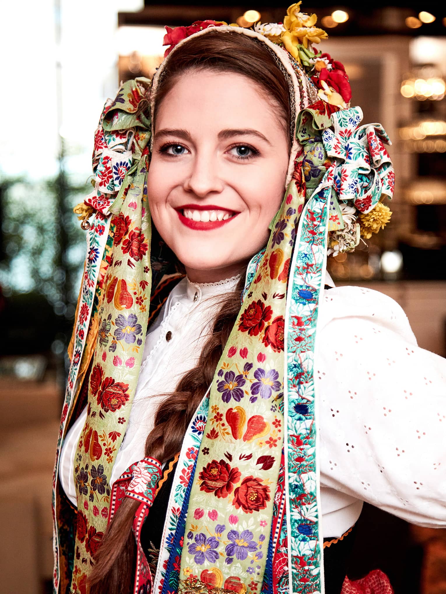 Woman dressed in traditional Czech costume with hands on hips, smiling