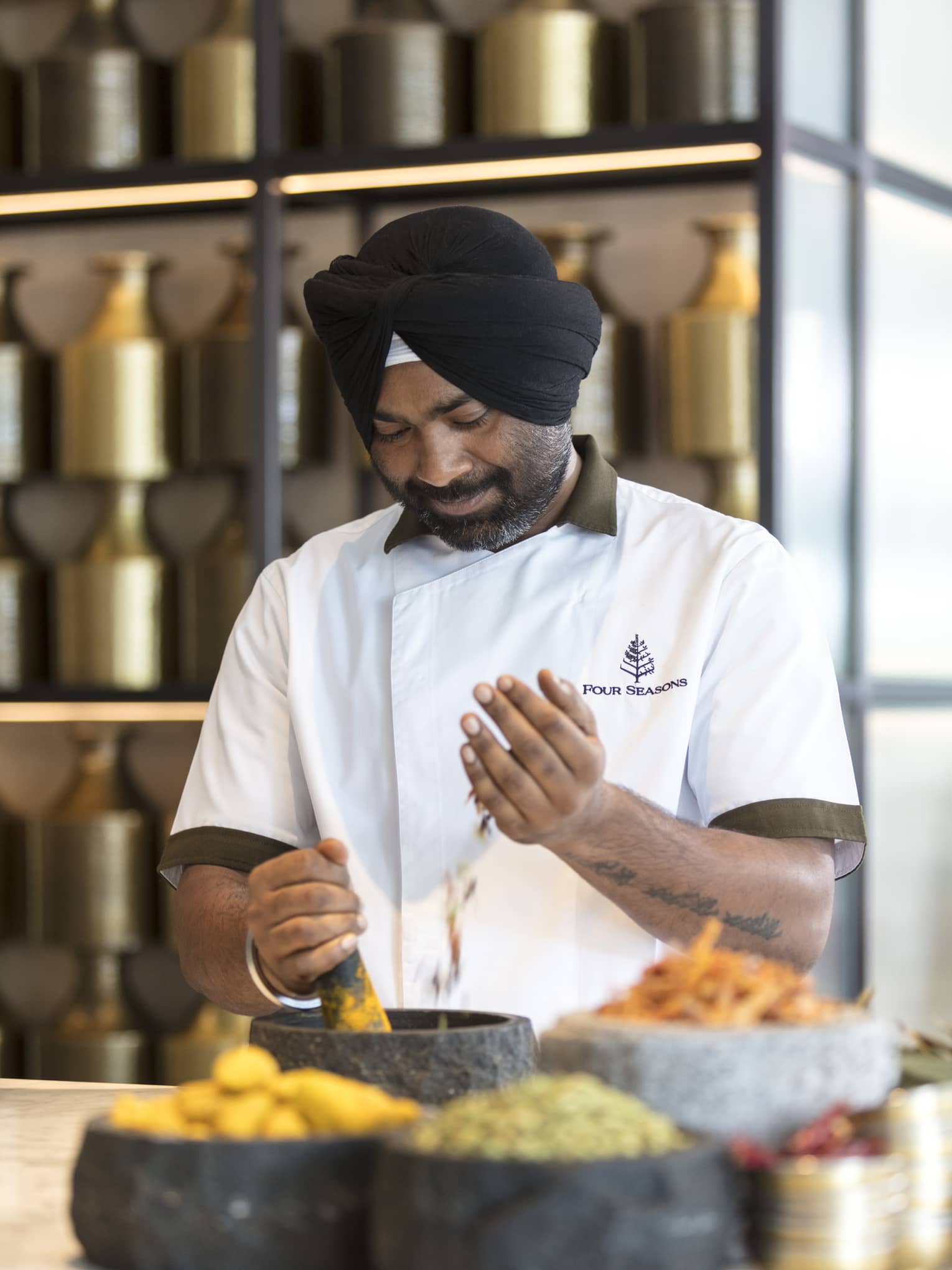 A chef uses a pestle and mortar to grind fresh herbs