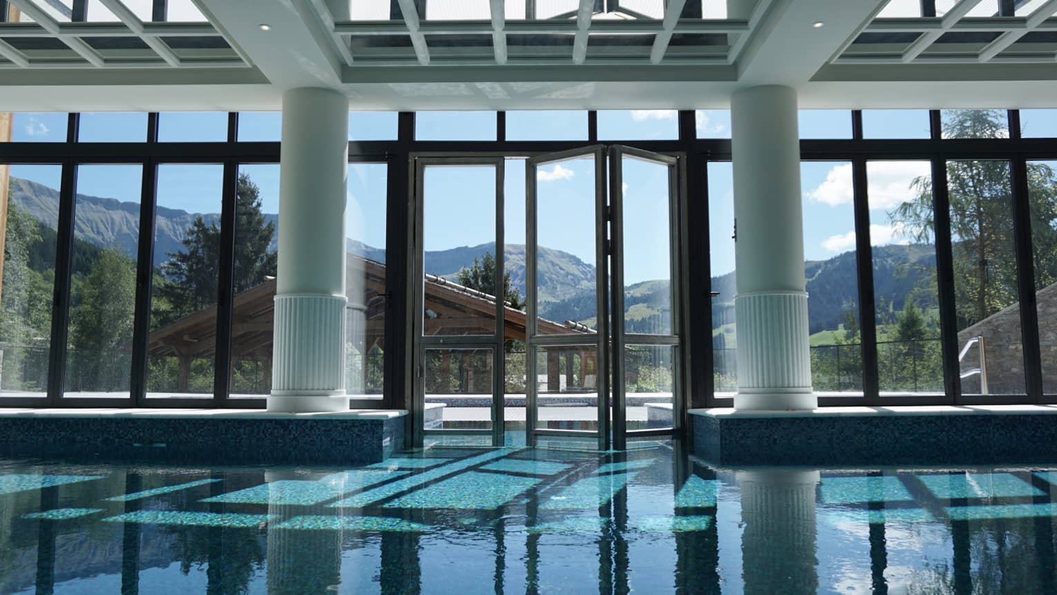 Large white pillars, beams, skylights over indoor swimming pool