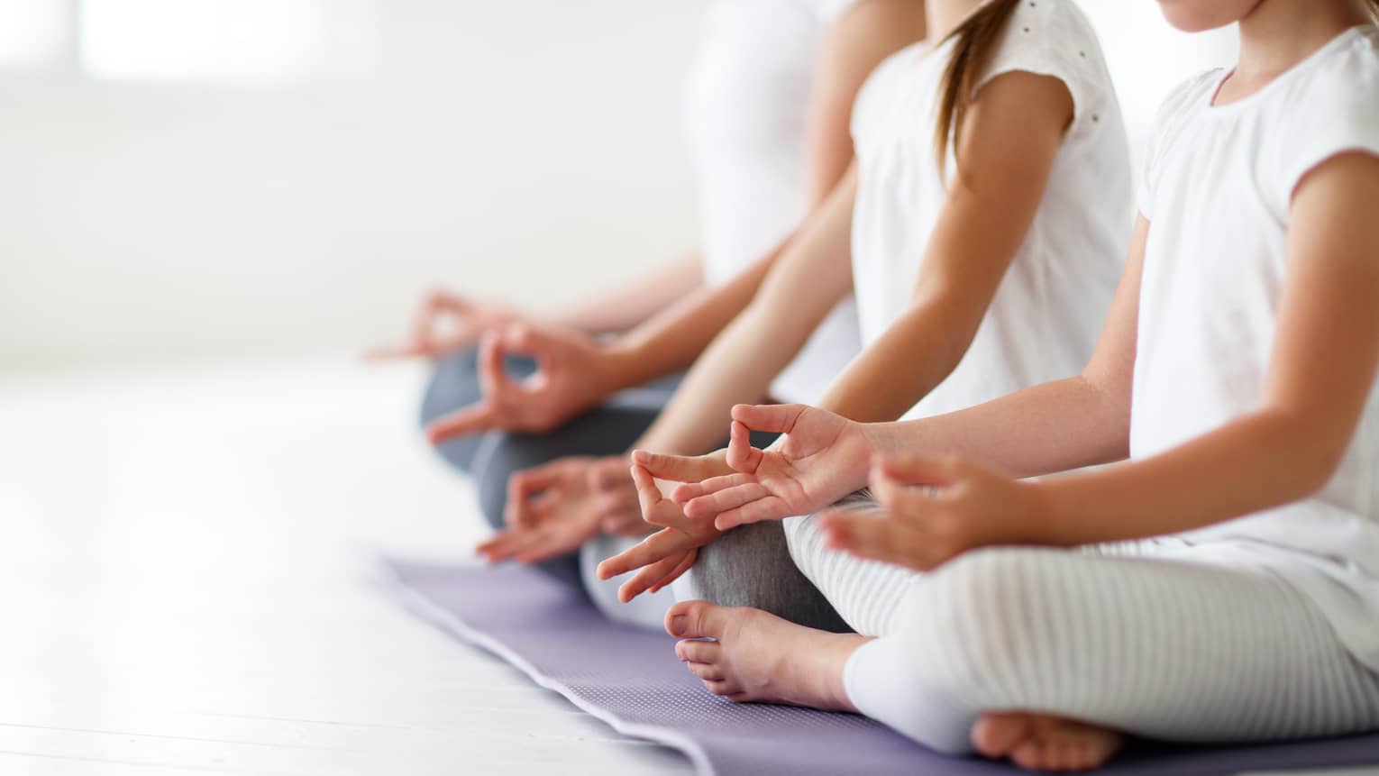 Young girls sit in cross-legged yoga pose