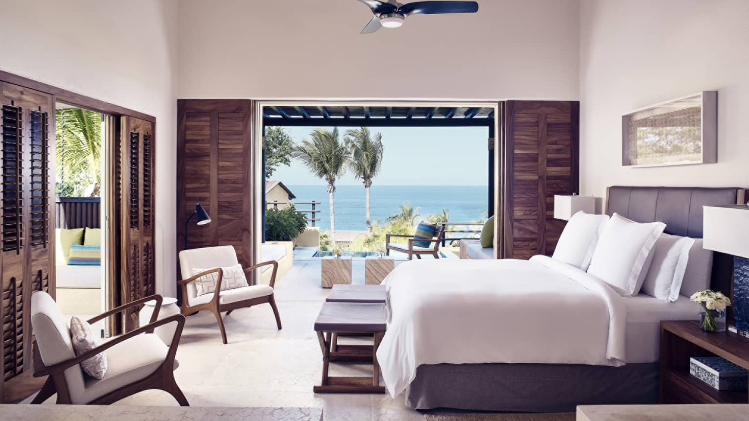 Bedroom with king bed, two arm chairs, walk-out ocean-view terrace