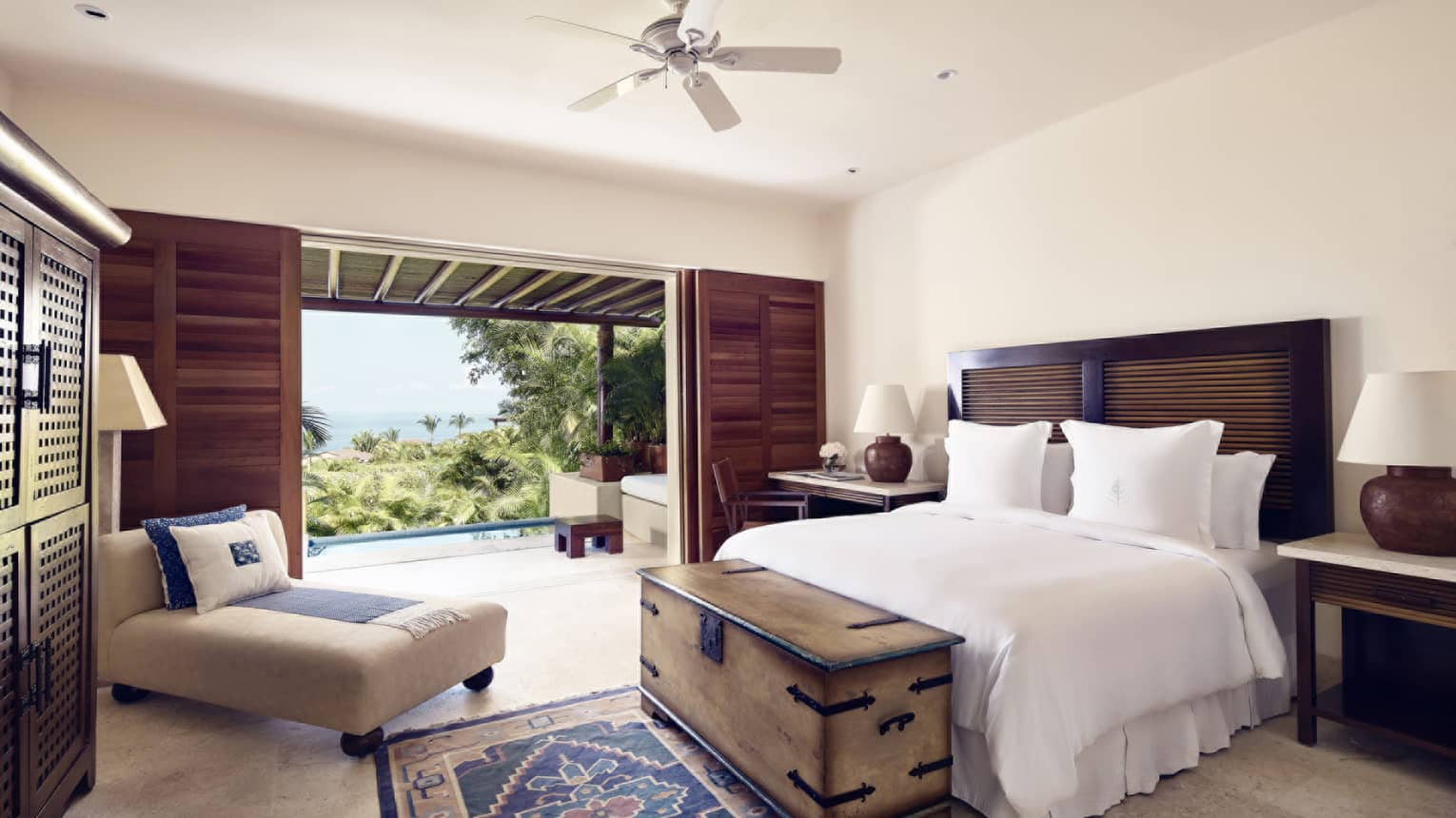 Bedroom with king bed, chest, chaise chair, walk-out terrace