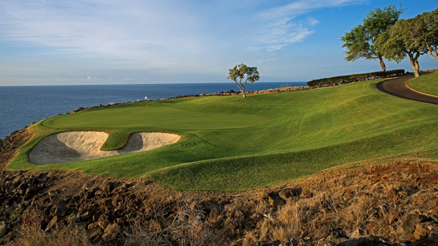 An oceanside golf course under blue skies