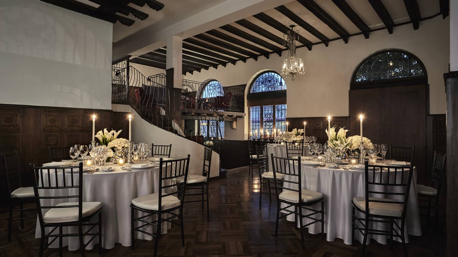 Small tables with candles by spiral staircase in Los Rosales event space