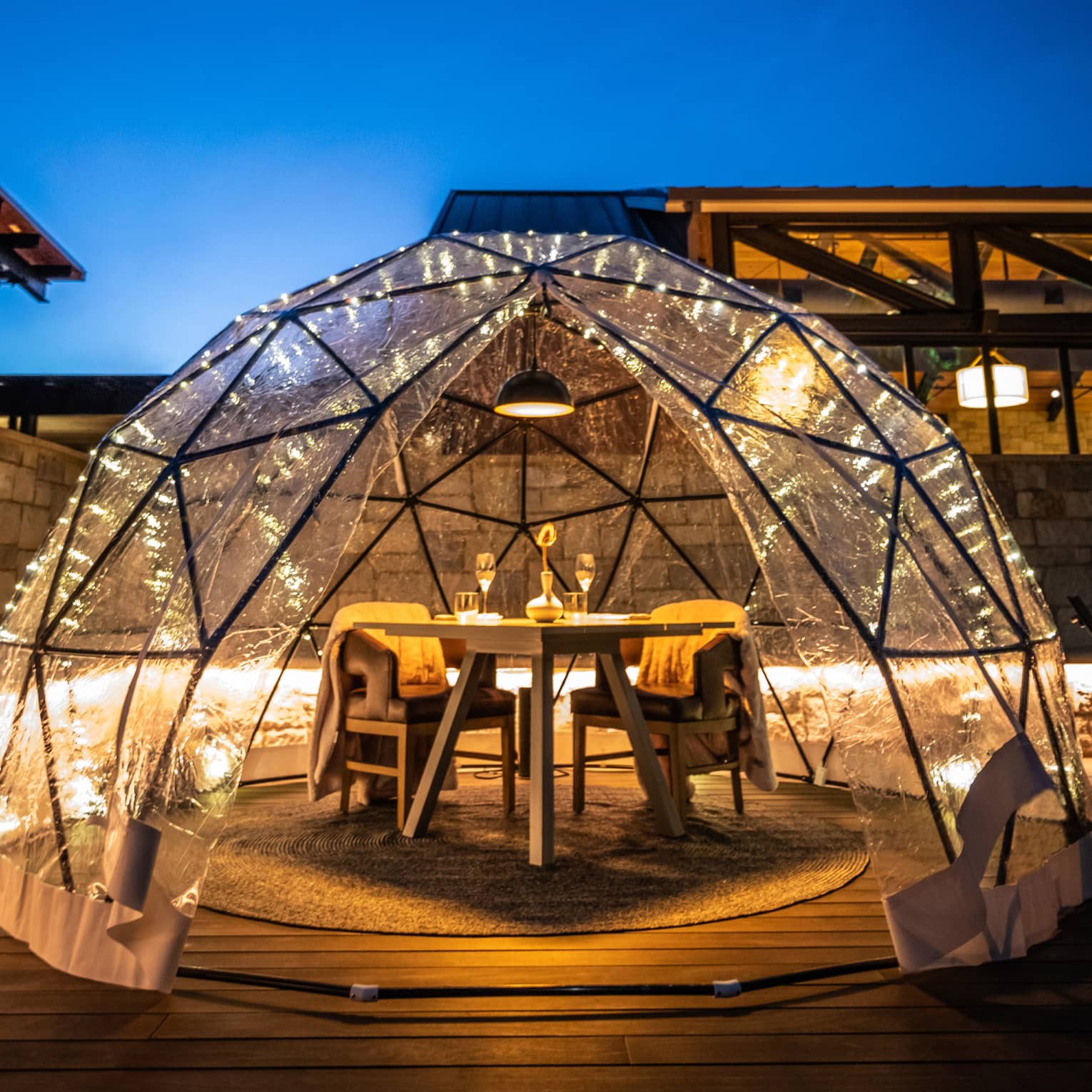 Dining table and chairs set up outside with an igloo covering.