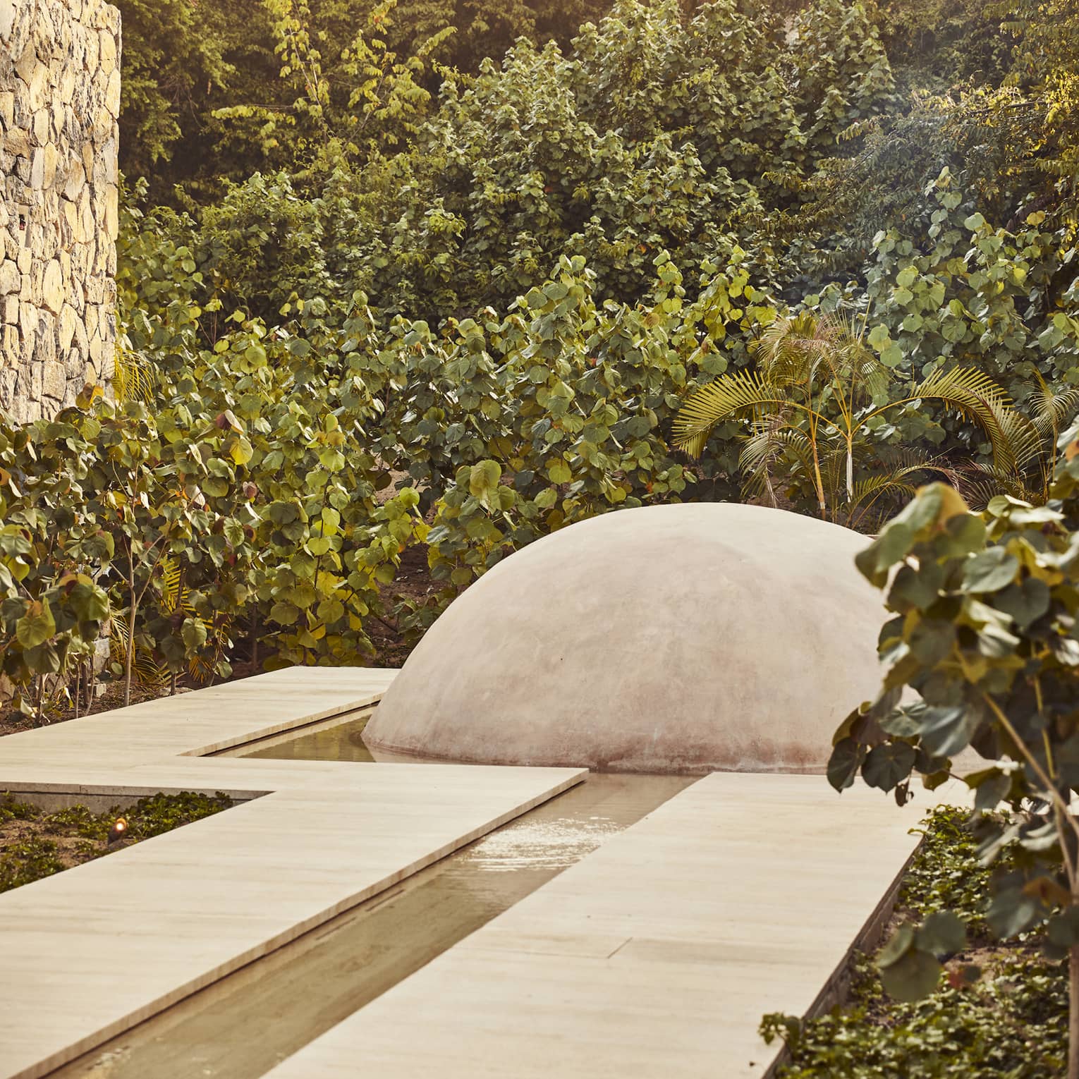 Pathway that leads to a dome surrounded by trees and leaves.
