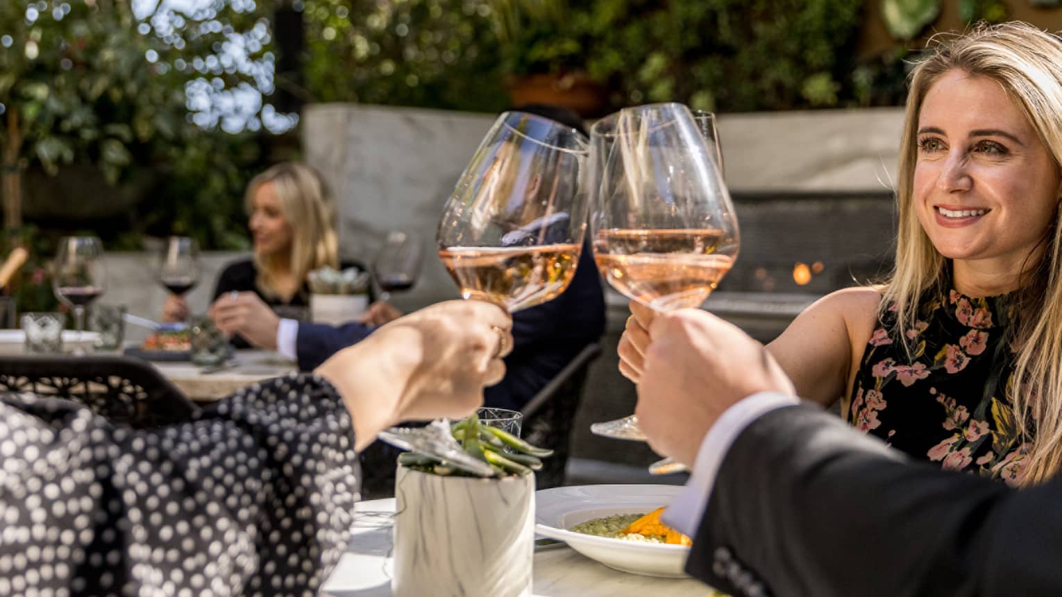 A group toasts glasses of wine on an outdoor patio