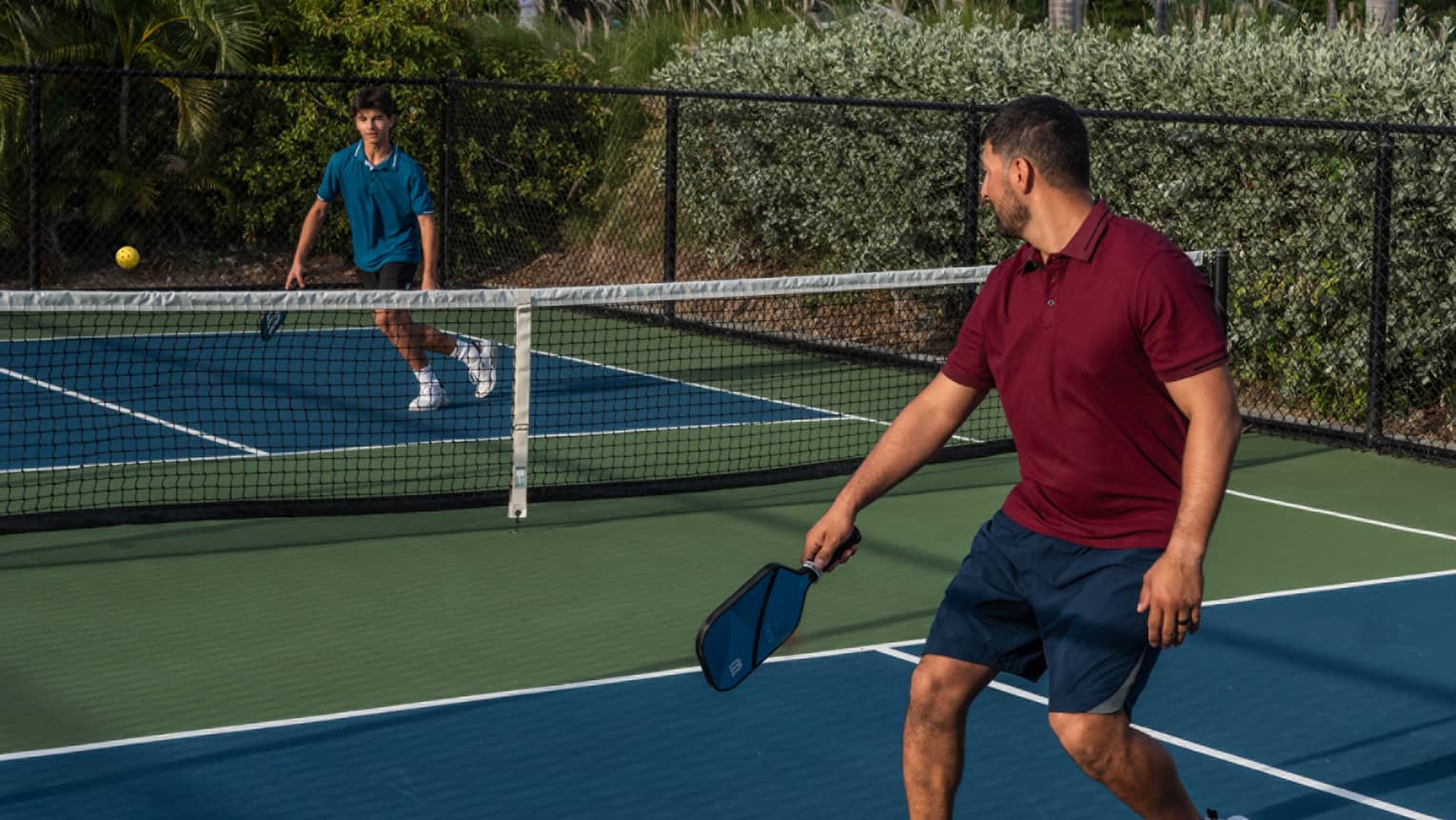 Guests playing pickleball on a pickleball court surrounded by palm trees