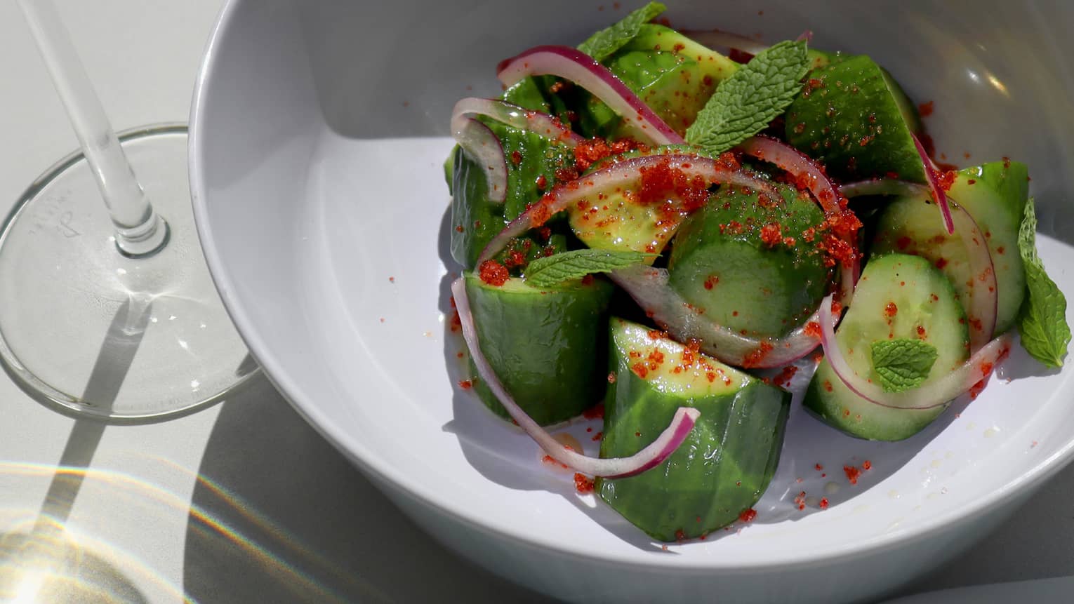 A cucumber salad in a white bowl.