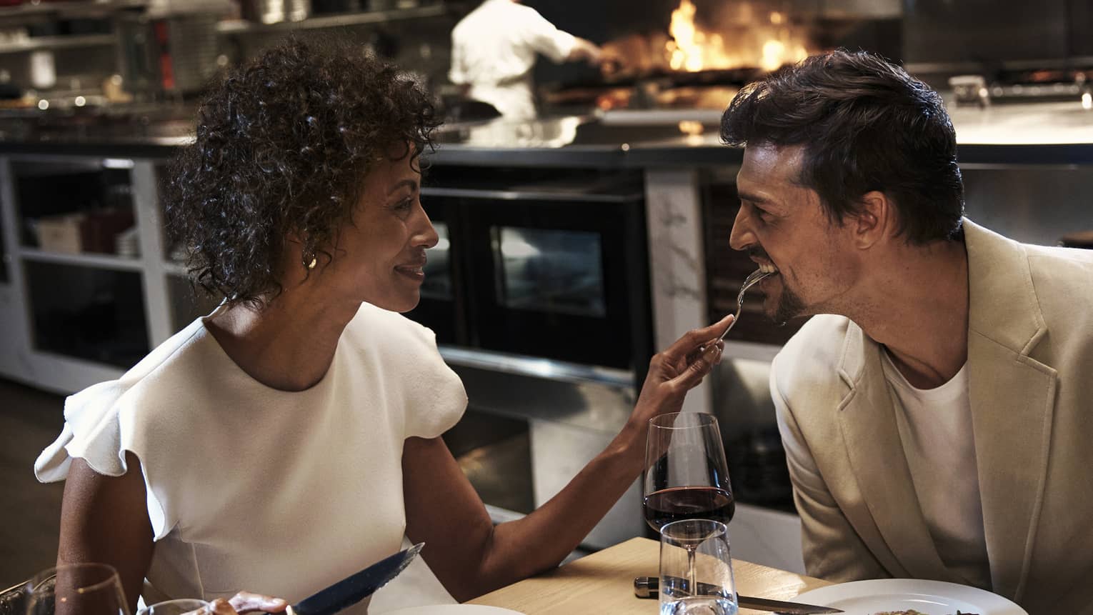 Two guests sitting at a dining table with the restaurant?s kitchen in the background