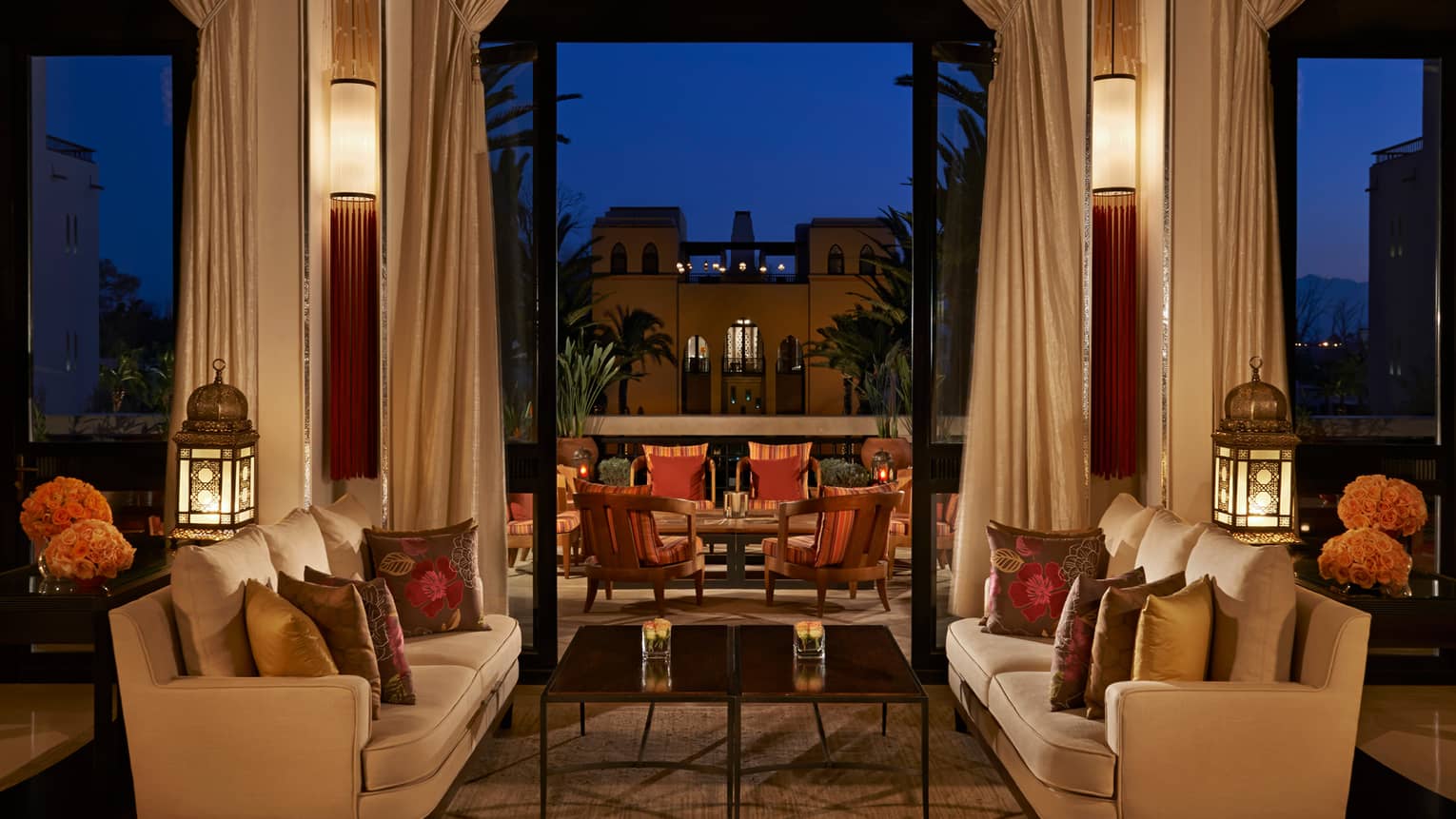 White sofas around table in Inara Lounge at night, building, lights against dark sky