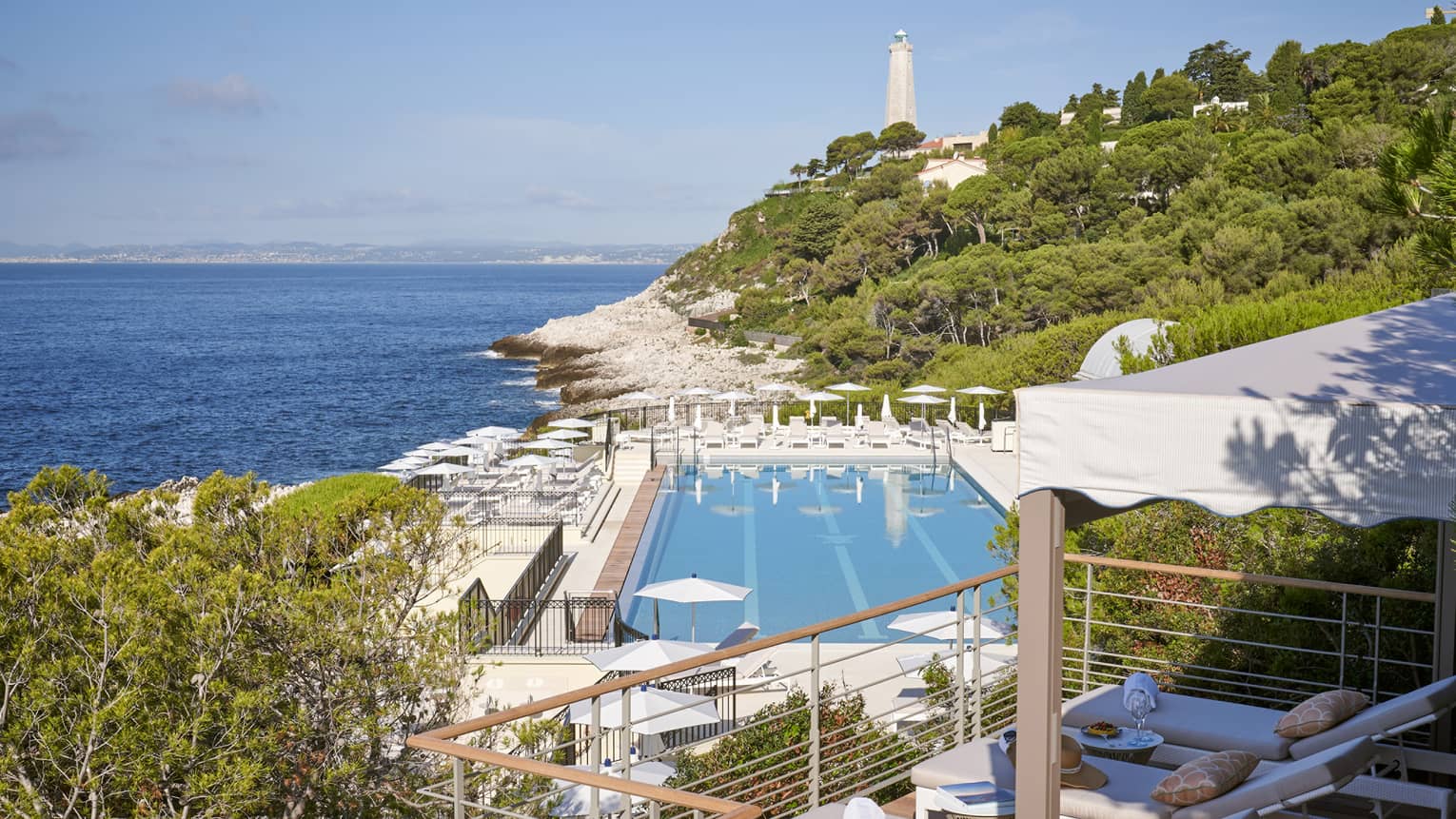 View from terrace of Club Dauphin pool, Mediterranean, green hillside and lighthouse