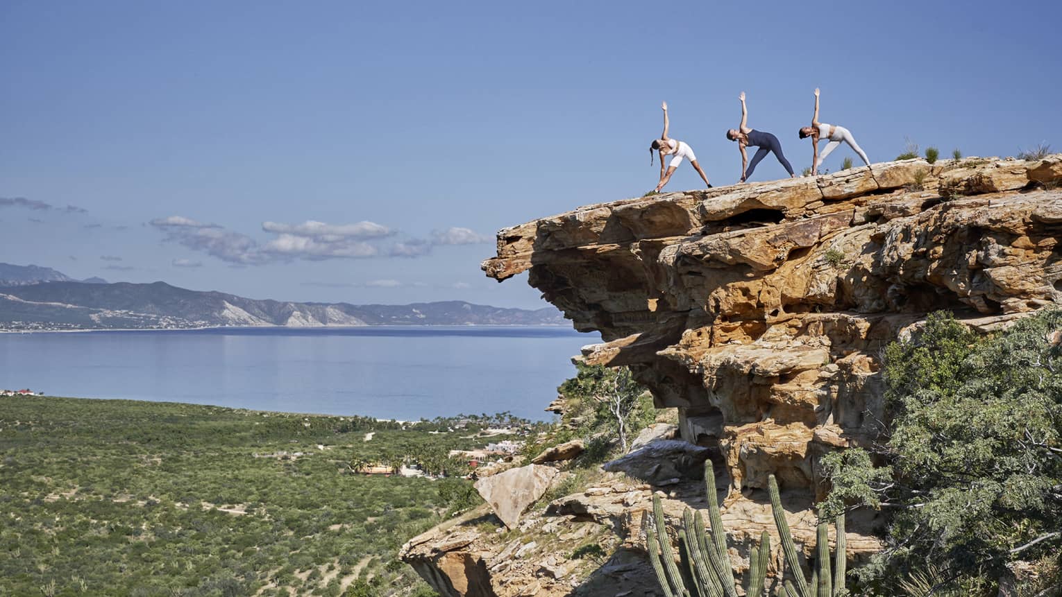 People doing yoga on a cliff.