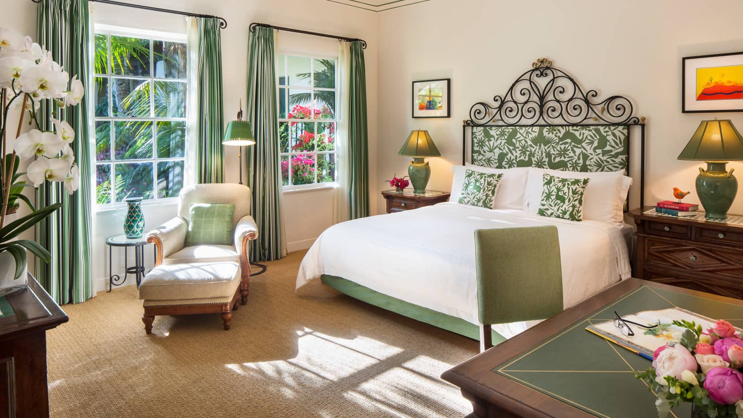 Riviera Room white armchair, ottoman, green pillow under sunny windows by bed, desk