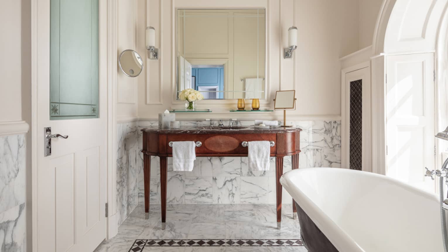 Bathroom with marble accents, large soaking tub, double wooden vanity, mirror