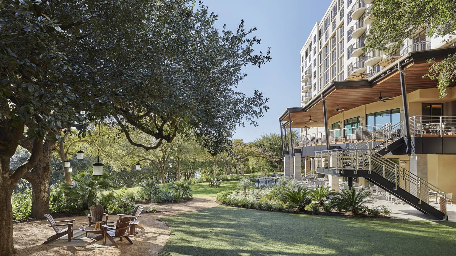 Exterior of Four Seasons Austin hotel with outdoor patio next to large tree and river