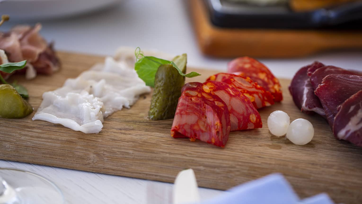 A charteurtie board with salami, cheese and onions on a table