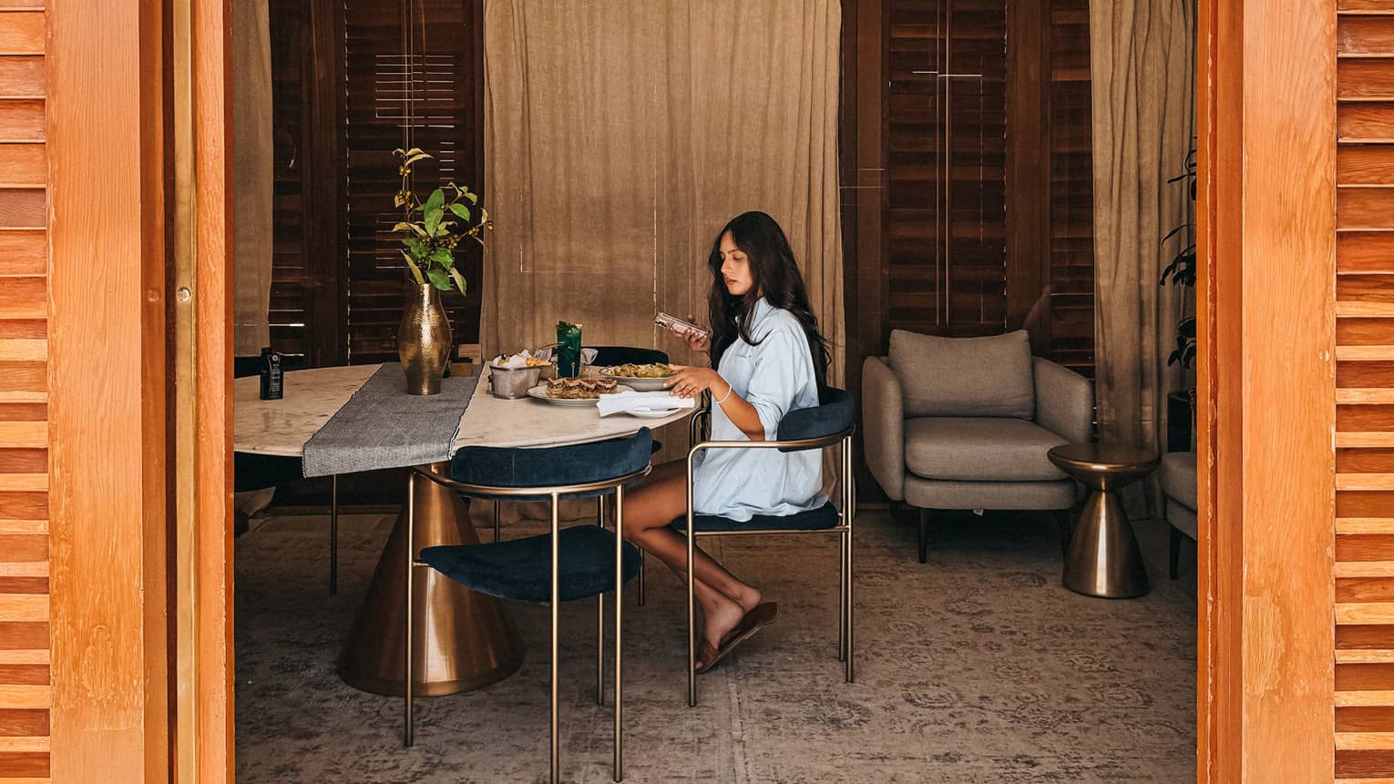Guest sits inside a cabana at a marble dining table