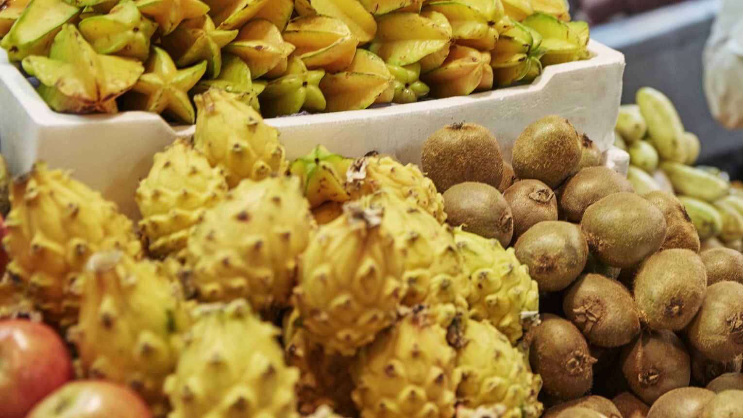 Chef smells tropical fruit at stand in market 