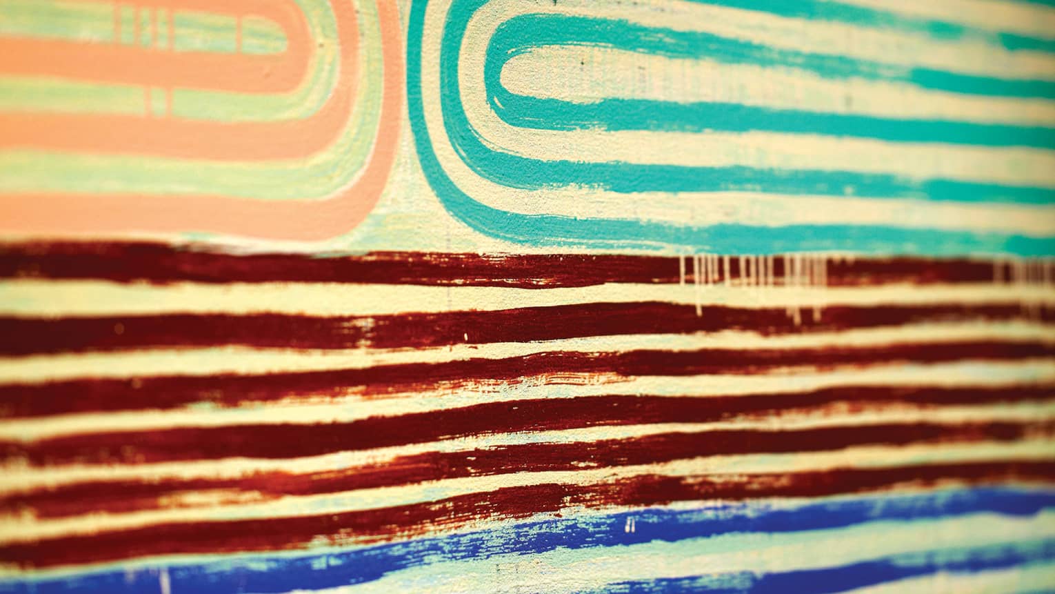 Close-up of pink, teal, red and blue lines of paint in pattern on canvas