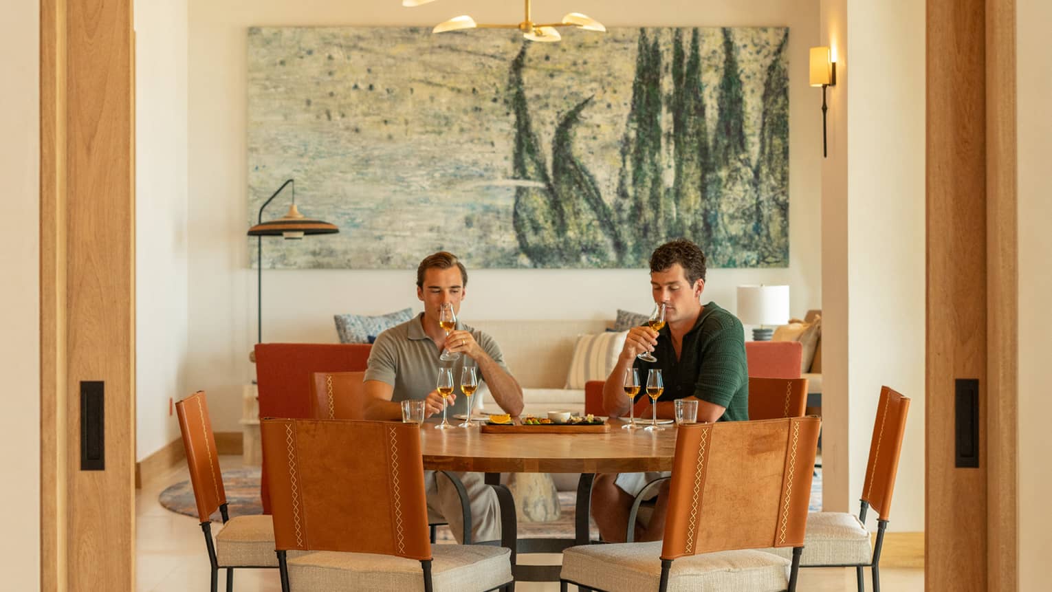 Two people sit at round table in dining room, tasting agave