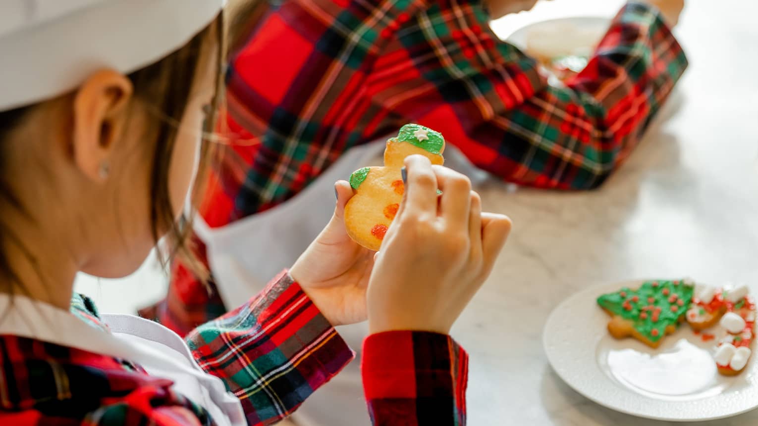 Two kids decorate holiday cookies