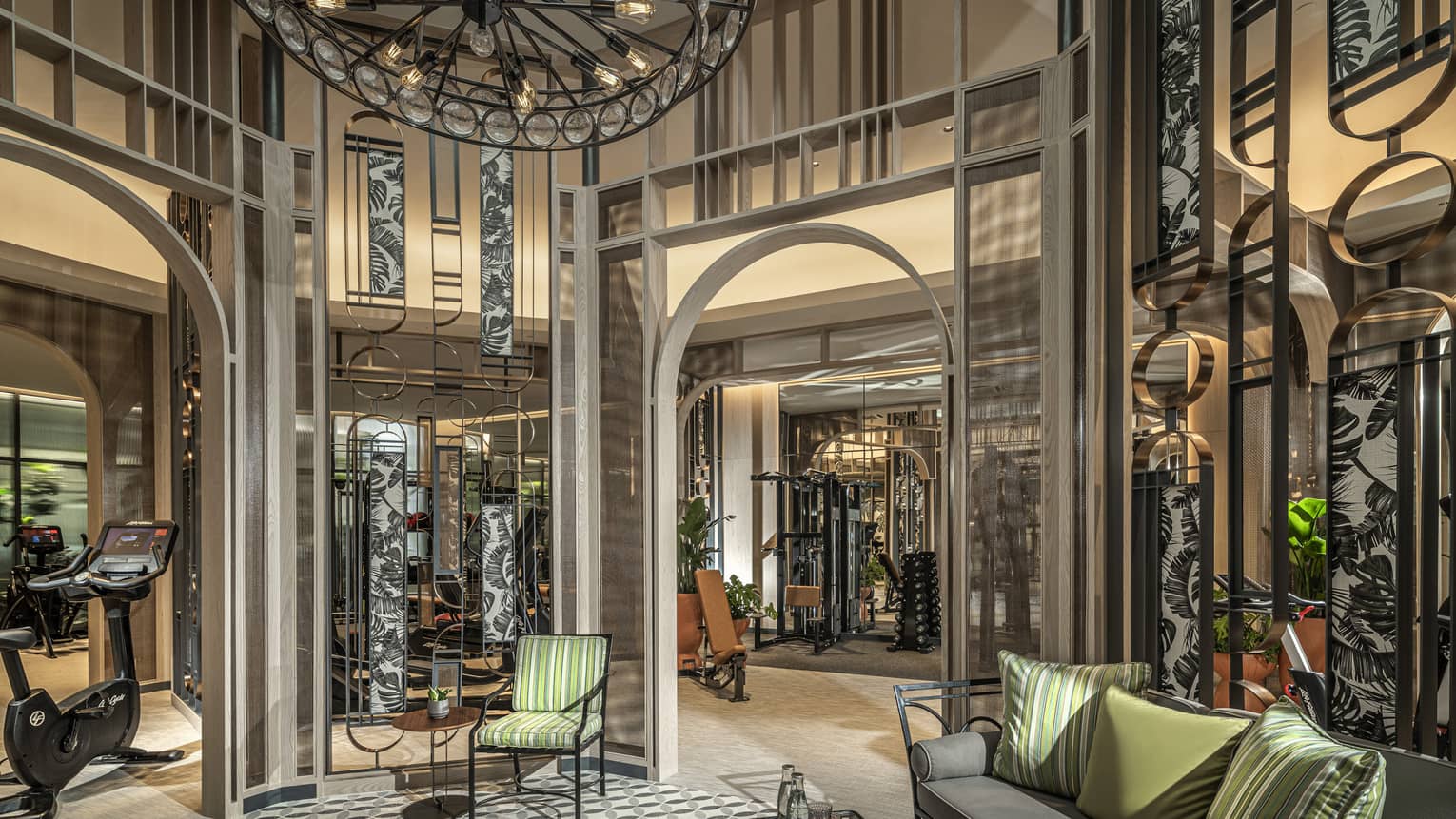 Fitness Centre lobby with high ceilings, round wrought-iron chandelier, sofa with green accent pillows