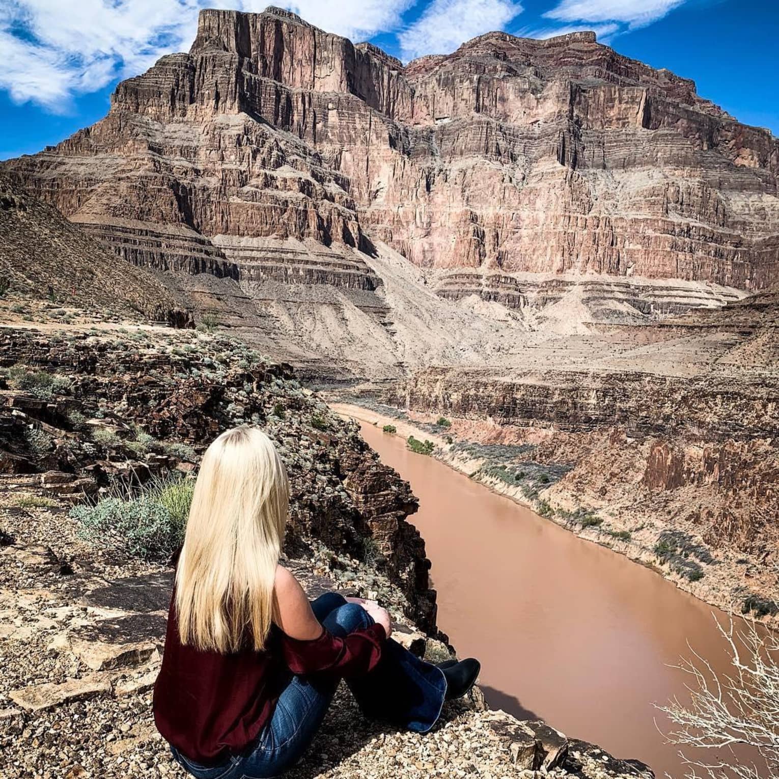 Back of woman sitting on cliff, looking out over Grand Canyon