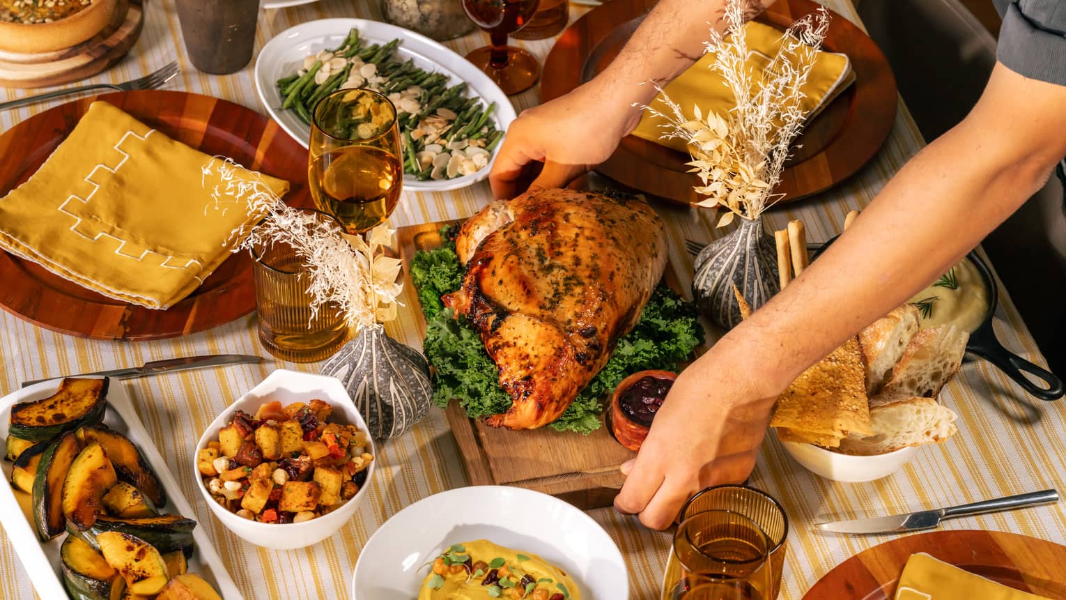 Whole roasted turkey being placed in the centre of a table filled with holiday dishes