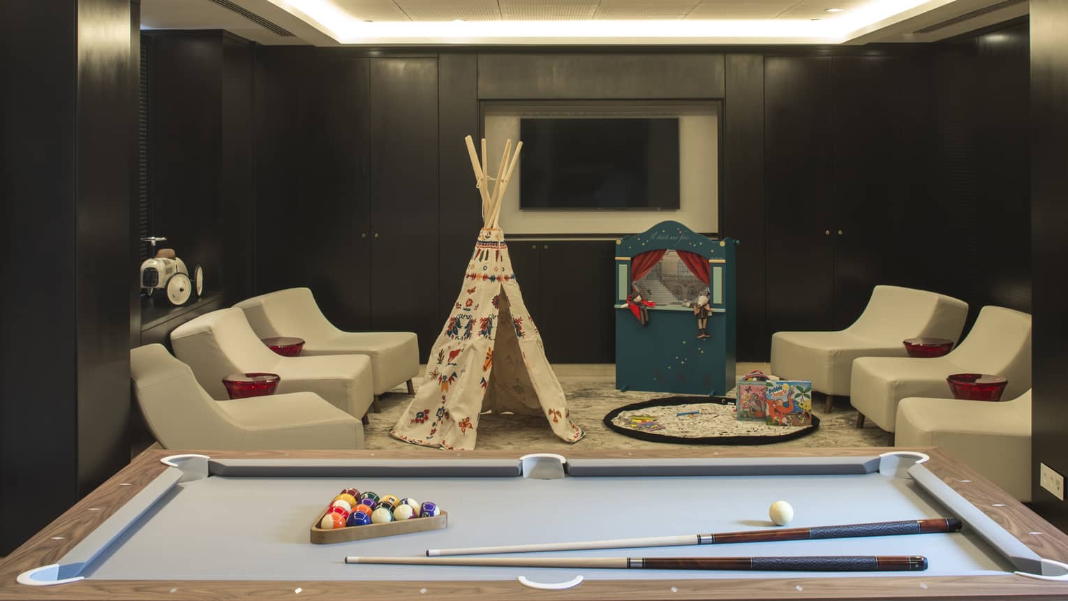Billiards table in front of white chairs, play tent, puppet theatre in Kids Club