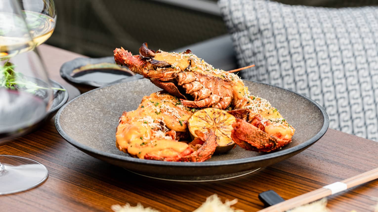 Spiny Lobster Thermidor on brown ceramic dish set on a wooden table with chopsticks