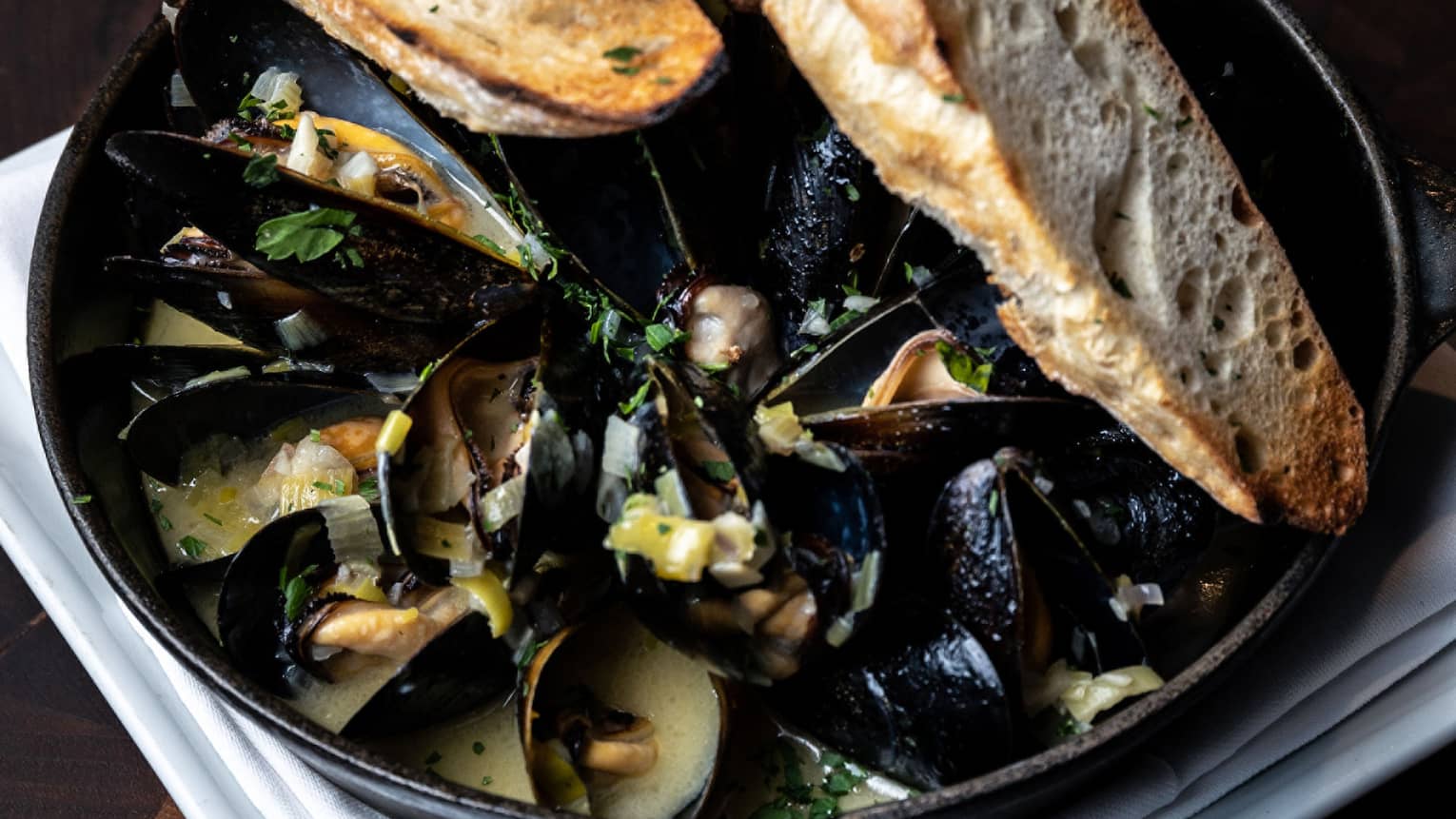 Steamed Pacific Mussels in an iron skillet with a toasted baguette