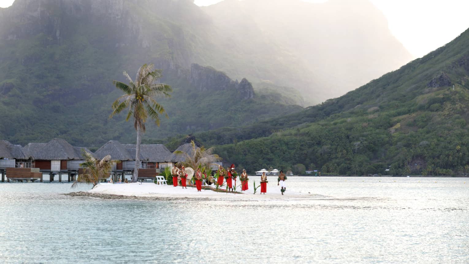 View across water to wedding ceremony on beach, misty Bora Bora mountain