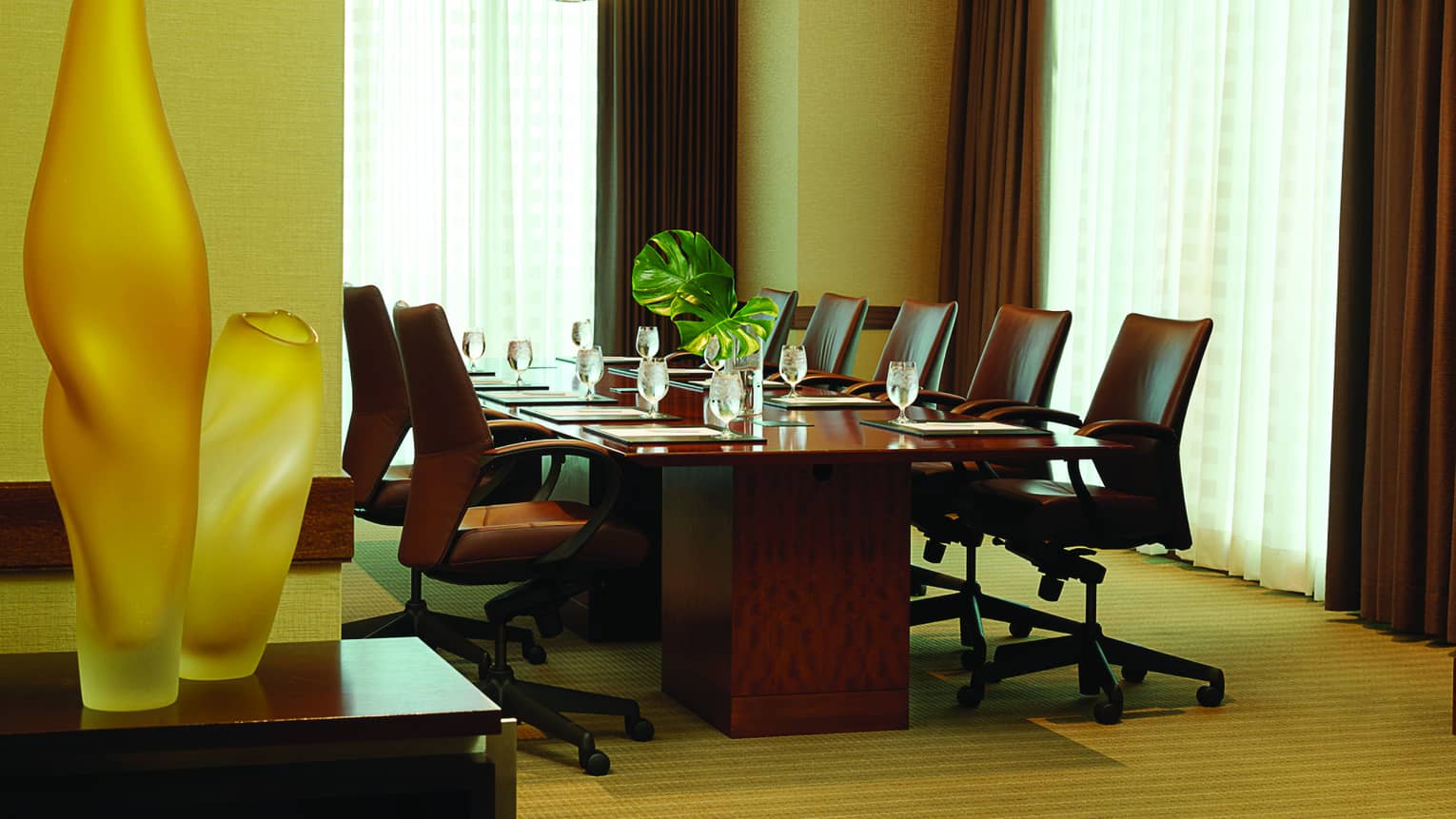 Frosted glass vases near boardroom meeting table and chairs