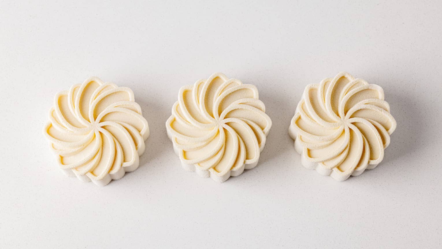 Three white floral-shaped pastries on a white backdrop
