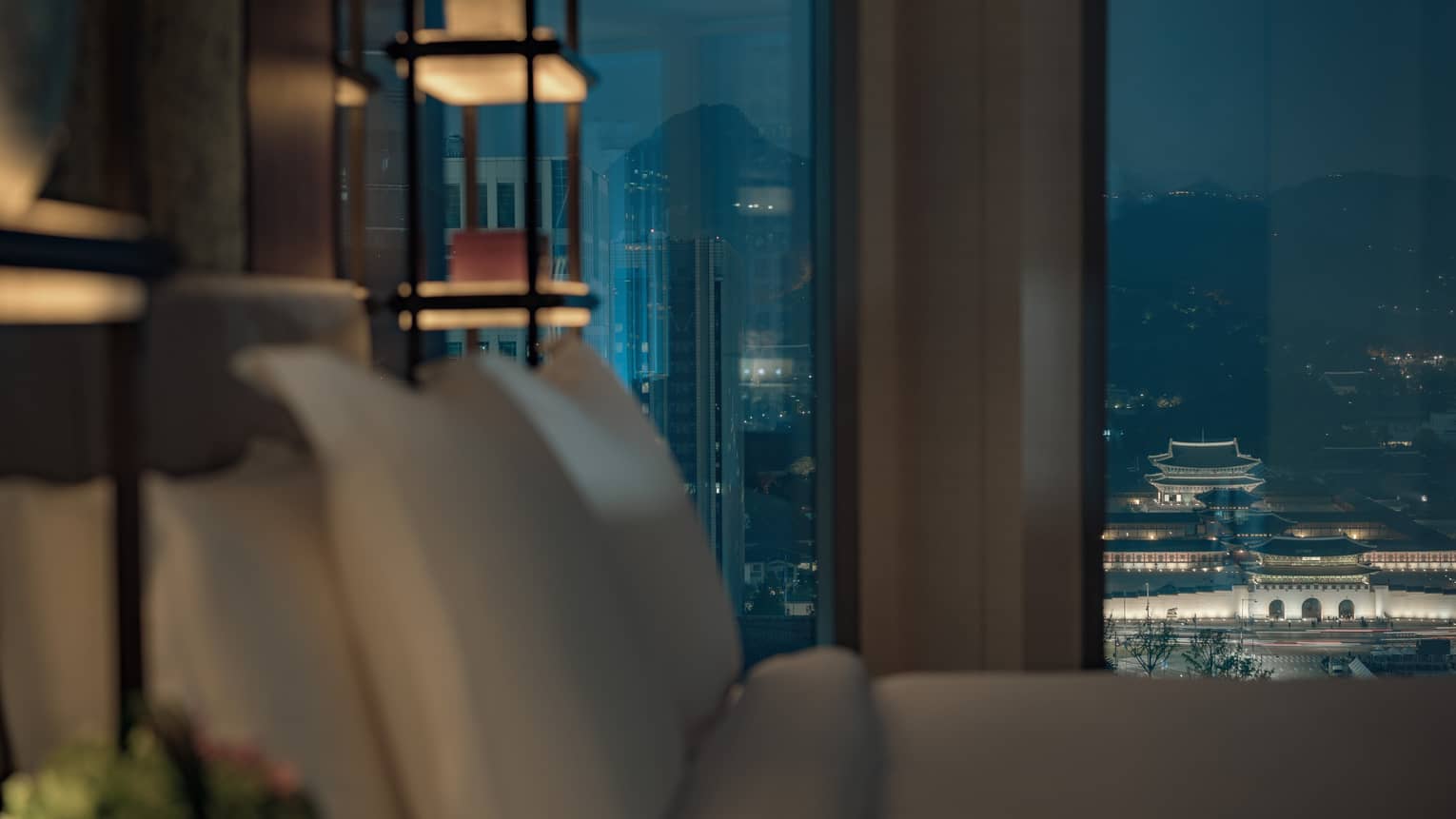 Palace-View Executive Suite close-up of hotel bed pillows in front of large window at night, city lights