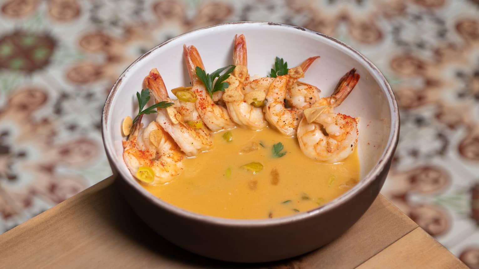 Shrimp in a yellow sauce served in a ceramic bowl.