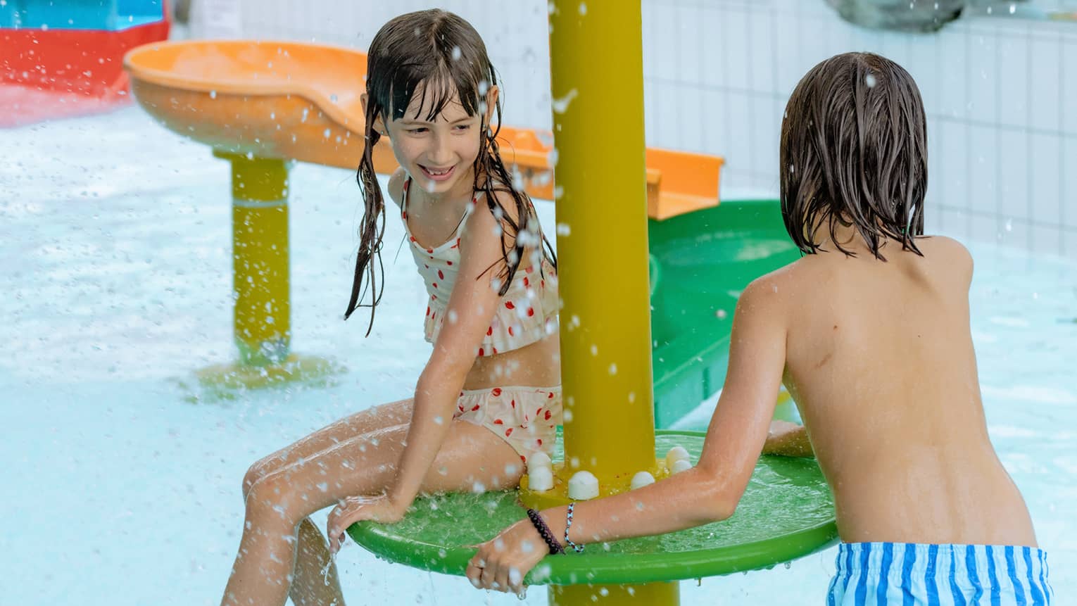 Two children playing on colourful feature of an indoor pool
