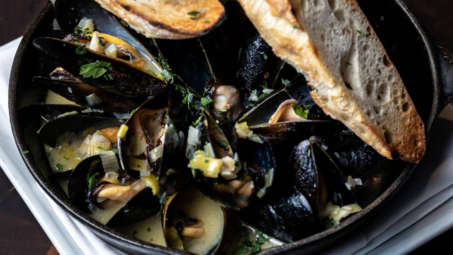 Steamed Pacific Mussels in an iron skillet with a toasted baguette